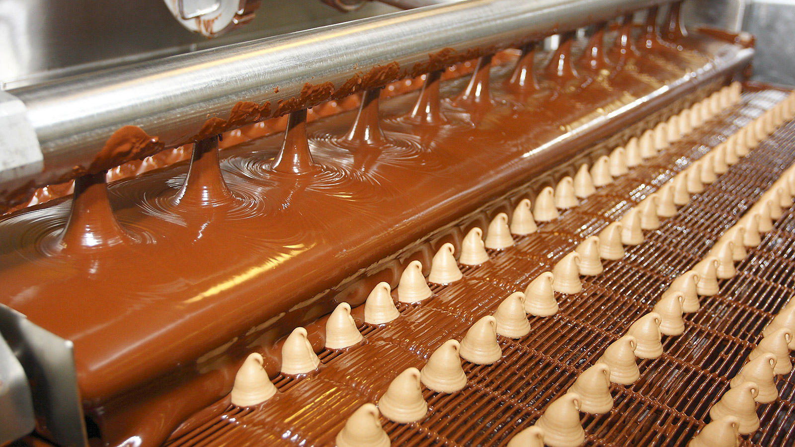 candy being covered in chocolate on a production line