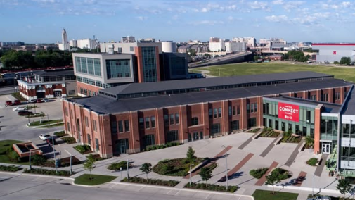 Nebraska Innovation Campus conference center; brick building with sidewalks, trees, and open space under a blue sky.