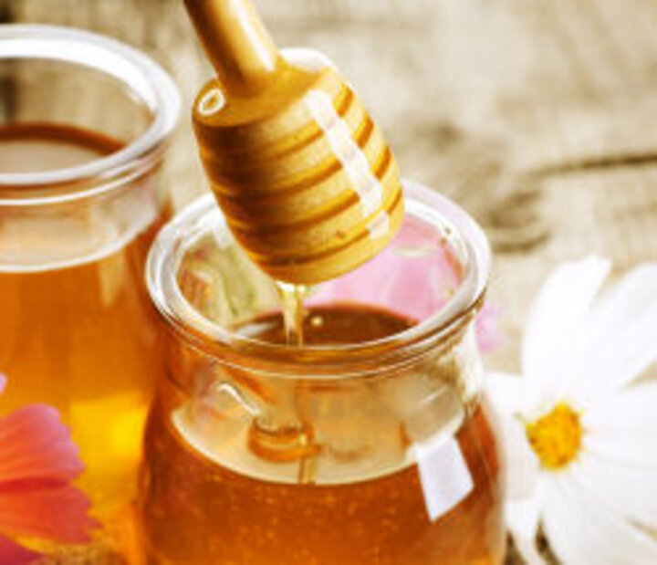 photo of jar of honey with honey spoon dripping